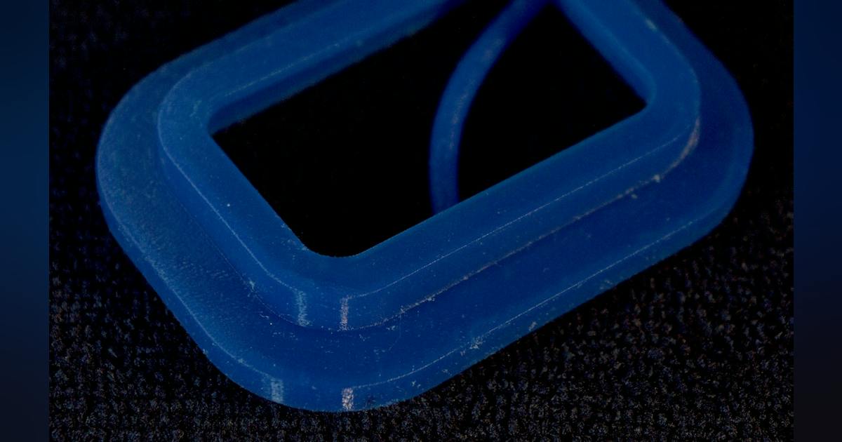 A flexible blue silicone gasket on a dark background.