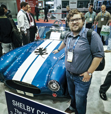 Andrew Finkle beside a 3D-printed Shelby Cobra at an exhibition.
